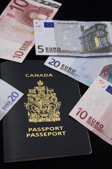 Close-up of five, ten, twenty Euro paper currency bank notes on top of Canadian passport on black background, Studio Composition, Quebec, Canada, North America