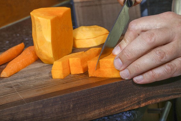 South German cuisine, butternut squash, butternut pumpkin, pumpkin cutting, preparation of oven vegetables, pumpkin, fruit vegetables, fruit, carrots, celery root, cutting board, wooden board, healthy cooking, vegetarian, vegan, autumn cuisine, pumpkin dishes, food, studio, man's hand, knife, Germany, Europe