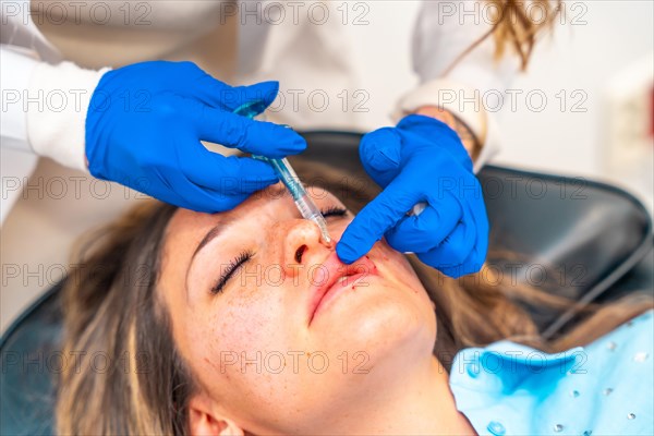 Close-up of plastic surgeon injecting botox to the adult caucasian woman's face in a clinic