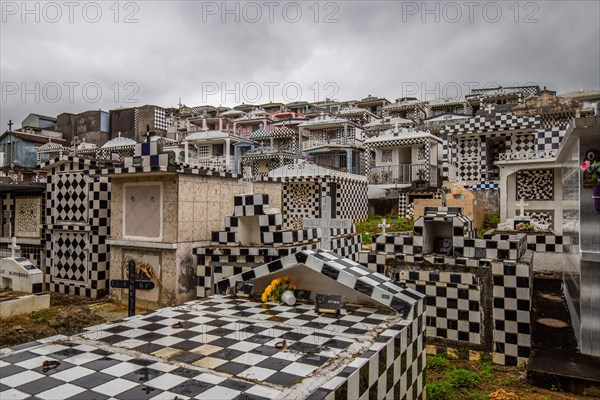 Famous cemetery, many mausoleums or large tombs decorated with tiles, often in black and white. Densely built buildings under a dramatic cloud cover Cimetiere de Morne-a-l'eau, Grand Terre, Guadeloupe, Caribbean, North America