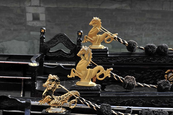 Several gilded sculptures on the black gondolas against a dark background, Venice, Veneto, Italy, Europe