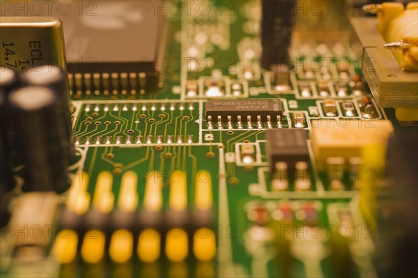 Close-up of green and golden lighted yellow electronic computer circuit board with capacitors, microchips, silver solder points and lines, Studio Composition, Quebec, Canada, North America