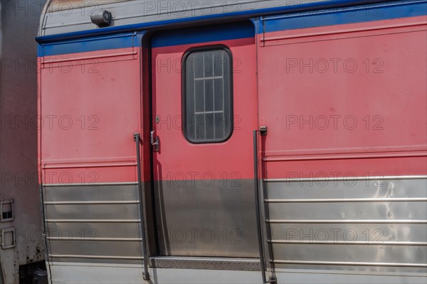 Red and silver train carriage door with metal handles, in South Korea