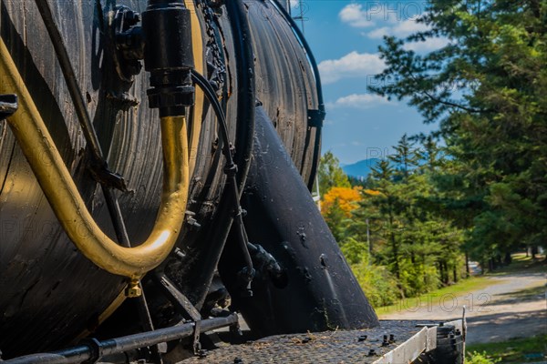 Side view of a vintage locomotive with blue sky, autumn trees, and mountains in the background, in South Korea