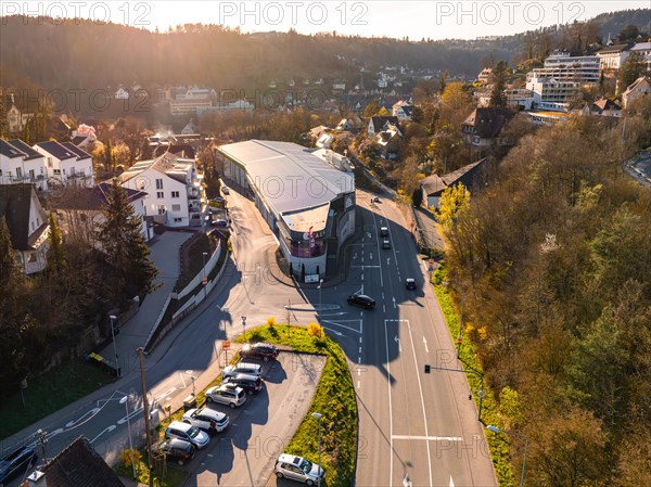 Drone view of a large commercial building surrounded by streets and cars at sunset, Calw, Black Forest, Germany, Europe