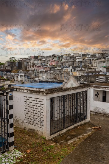 Famous cemetery, many mausoleums or large tombs decorated with tiles, often in black and white. Densely built buildings under a sunset Cimetiere de Morne-a-l'eau, Grand Terre, Guadeloupe, Caribbean, North America
