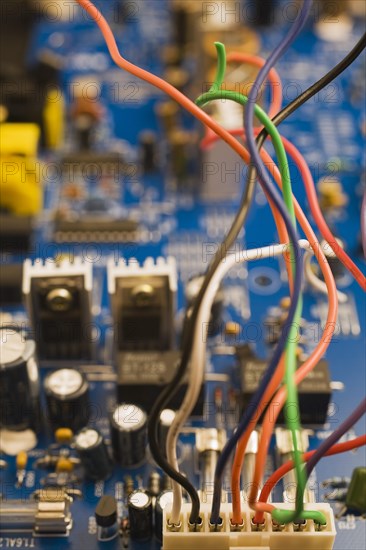 Close-up of colorful insulated electrical wires and blue computer circuit board with capacitors and various electronic components, Studio Composition, Quebec, Canada, North America