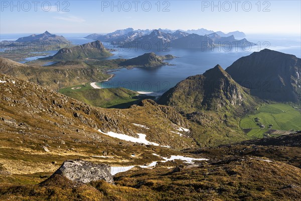 Landscape with sea and mountains. Descent from Himmeltindan mountain. View of the light-coloured sandy beaches of Vik (Vik Beach) and Haukland (Haukland Beach) and Vik Bay (Vikbukta), with the mountains Mannen and Veggen on the right. In the back left the mountains Offersoykammen and Skottinden. In the background the mountains of Flakstadoya. Vestvagoya, Lofoten, Norway, Europe