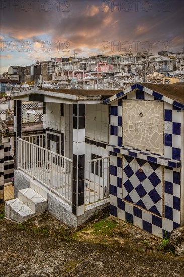 Famous cemetery, many mausoleums or large tombs decorated with tiles, often in black and white. Densely built buildings under a sunset Cimetiere de Morne-a-l'eau, Grand Terre, Guadeloupe, Caribbean, North America