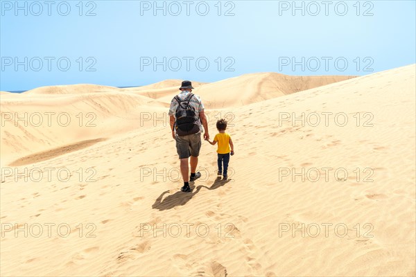 Father and son on vacation smiling in the dunes of Maspalomas, Gran Canaria, Canary Islands