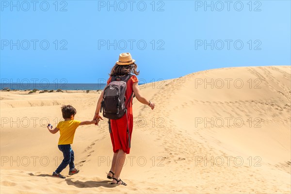 (Varios valores) Mother and son walking in the dunes of Maspalomas on vacation, Gran Canaria, Canary Islands