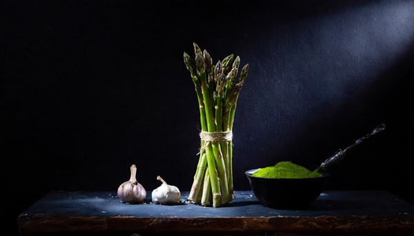 Asparagus and garlic cloves arranged on a stone board next to a bowl of powder, fresh green asparagus, AI generated, AI generated