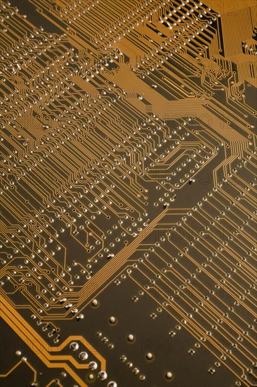 Close-up of golden orange lighted electronic computer circuit board with lines and silver solder points, Studio Composition, Quebec, Canada, North America