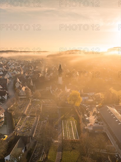 The first rays of sunlight illuminate a small town shrouded in morning mist, Gechingen, Black Forest, Germany, Europe