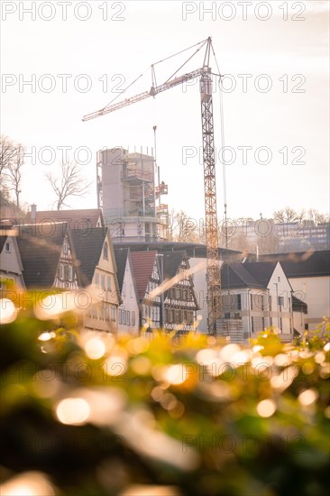 A construction crane towers over a building site against the backdrop of old half-timbered houses, Calw, Black Forest, Germany, Europe