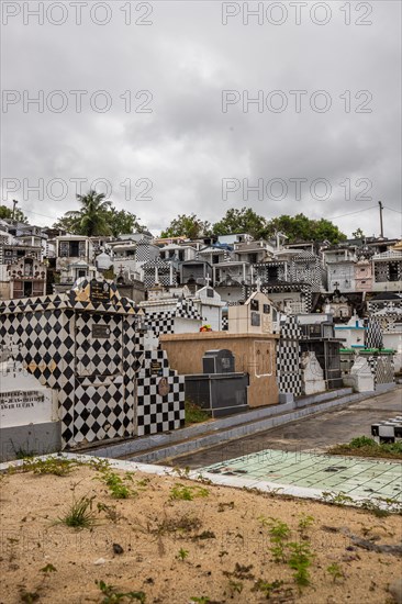 Famous cemetery, many mausoleums or large tombs decorated with tiles, often in black and white. Densely built buildings under a dramatic cloud cover Cimetiere de Morne-a-l'eau, Grand Terre, Guadeloupe, Caribbean, North America