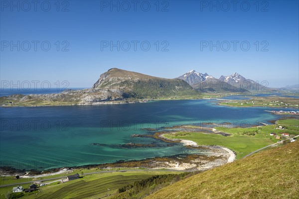 Landscape on the Lofoten Islands. View from the Hornsheia hiking area to the small village of Haug, the sea and the mountains Offersoykammen and Himmeltindan as well as the smaller Holandsmaelen. Good weather, blue sky. Vestvagoya, Lofoten, Norway, Europe