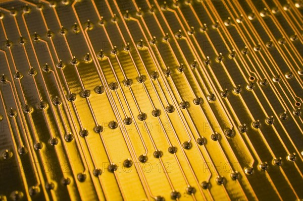 Close-up of golden yellow lighted electronic computer circuit board with lines and silver solder points, Studio Composition, Quebec, Canada, North America