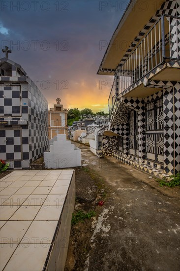 Famous cemetery, many mausoleums or large tombs decorated with tiles, often in black and white. Densely built buildings under a sunset Cimetiere de Morne-a-l'eau, Grand Terre, Guadeloupe, Caribbean, North America