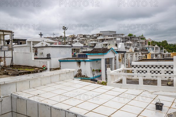 Famous cemetery, many mausoleums or large tombs decorated with tiles, often in black and white. Densely built buildings under a dramatic cloud cover Cimetiere de Morne-a-l'eau, Grand Terre, Guadeloupe, Caribbean, North America