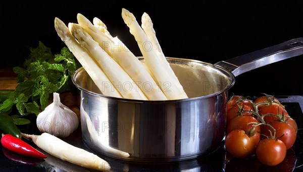 White asparagus spears in a pot next to fresh tomatoes and chilli, fresh white asparagus in a cooking pot, KI generated, AI generated