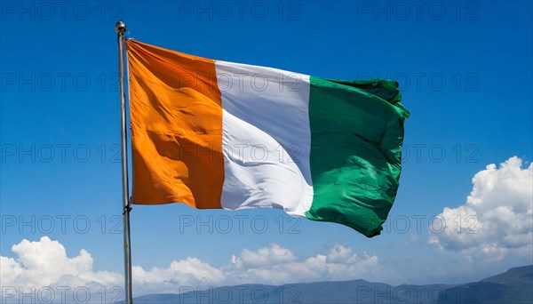 The flag of Ivory Coast flutters in the wind, isolated, against the blue sky