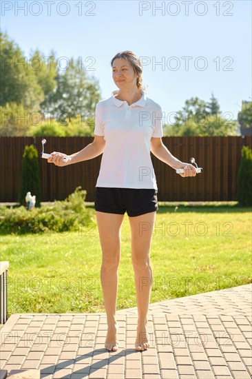 Active mid adult a woman jumps with a smart rope on backyard