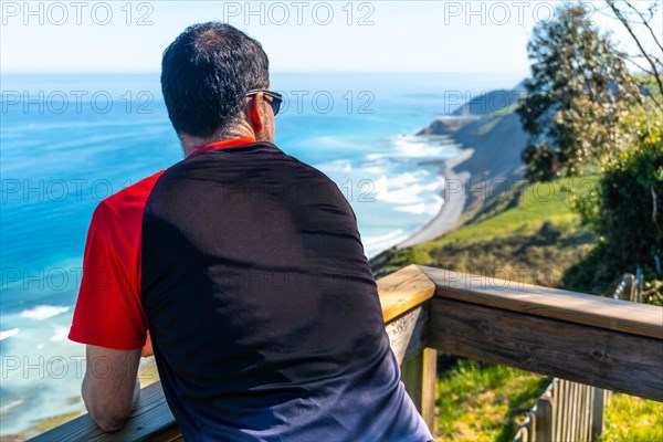 A tourist looking at the beautiful coastal landscape in the flysch of Zumaia, Gipuzkoa. Basque Country