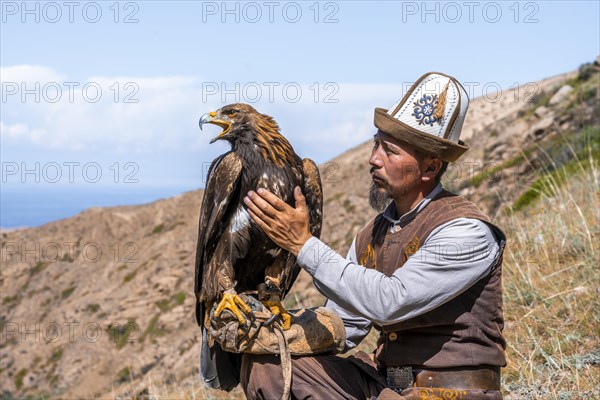 Traditional Kyrgyz eagle hunter with eagle in the mountains, hunting, near Bokonbayevo, Issyk Kul region, Kyrgyzstan, Asia