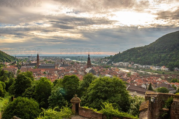 View over an old town with churches in the evening at sunset. This town lies in a river valley of the Neckar, surrounded by hills. Heidelberg, Baden-Wuerttemberg, Germany, Europe