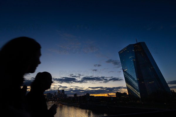 Two passers-by look over to the European Central Bank (ECB) in Frankfurt am Main in the evening, Frankfurt am Main, Hesse, Germany, Europe