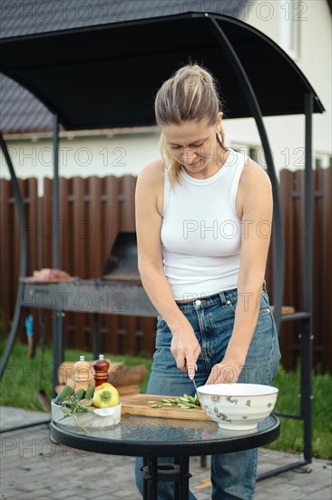 Mid adult woman cutting fresh cucumber for salad on backyard