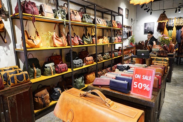 Strolling through the restored Tianzifang neighbourhood, interior view of a shop full of different leather bags with sales sign, Shanghai, China, Asia