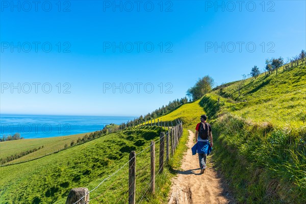 A hiker walking along a coastal path near the Zumaia flysch, Gipuzkoa. Basque Country