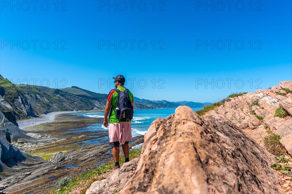 A male hiker in Algorri cove on the coast in the flysch of Zumaia, Gipuzkoa. Basque Country