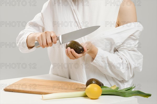 Unrecognizable woman cutting fresh avocado into halves. Concept of balanced eating