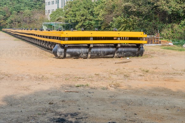 Large floating pier sitting on sandy ground with trees in background in South Korea