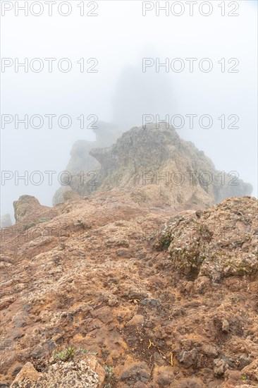 A rocky hillside with a foggy sky in the background. The fog is thick and the rocks are jagged and rough. The scene is desolate and eerie, with the fog adding to the sense of mystery and isolation