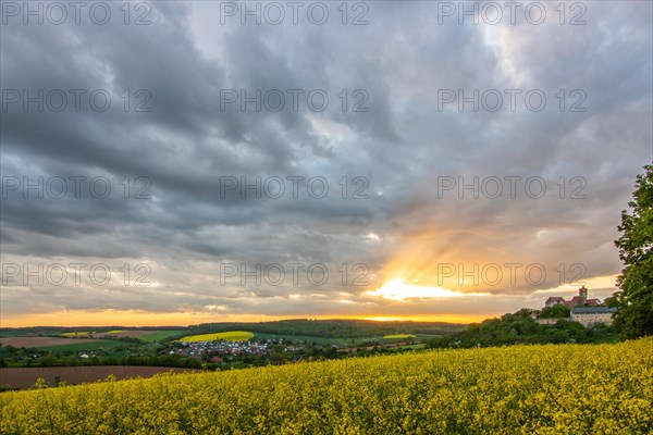 Landscape at sunrise. Beautiful morning landscape with fresh yellow rape fields in spring. Small castle in the yellow fields on a hill. Historic Ronneburg Castle in the middle of nature, Ronneburg, Hesse, Germany, Europe