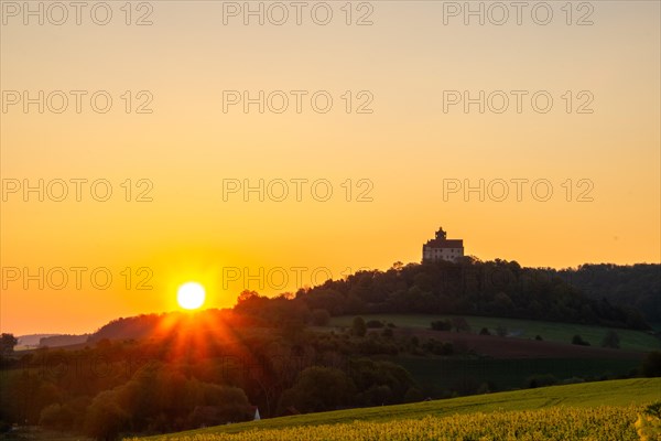 Landscape at sunrise. Beautiful morning landscape with fresh yellow rape fields in spring. Small castle in the yellow fields on a hill. Historic Ronneburg Castle in the middle of nature, Ronneburg, Hesse, Germany, Europe