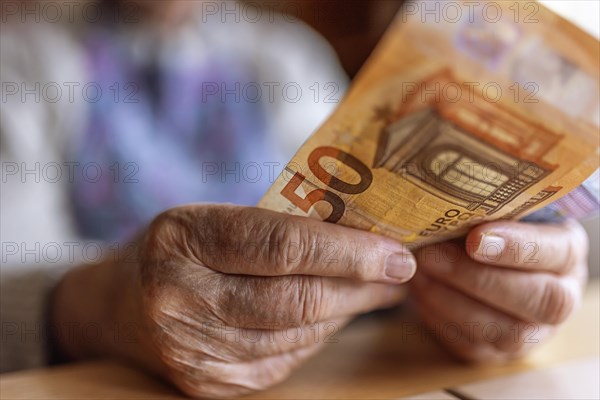 Wrinkled hands of a senior citizen with banknotes at home in her living room, close-up, Cologne, North Rhine-Westphalia, Germany, Europe