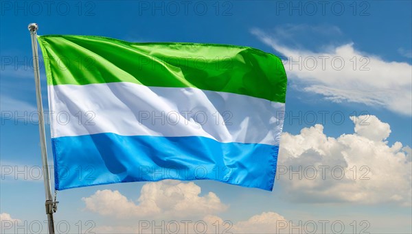 The flag of Sierra Leone, fluttering in the wind, isolated, against the blue sky