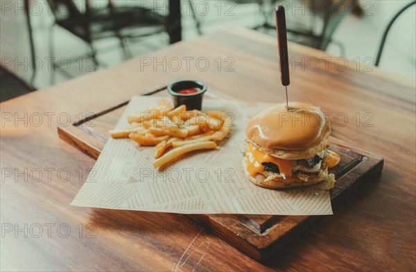 Appetizing burger with fries served on a wooden table. Traditional hamburger with fries served on a restaurant table