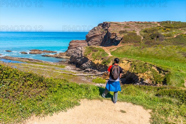 A hiker on a coastal path in the Algorri cove of the Zumaia flysch, Gipuzkoa. Basque Country