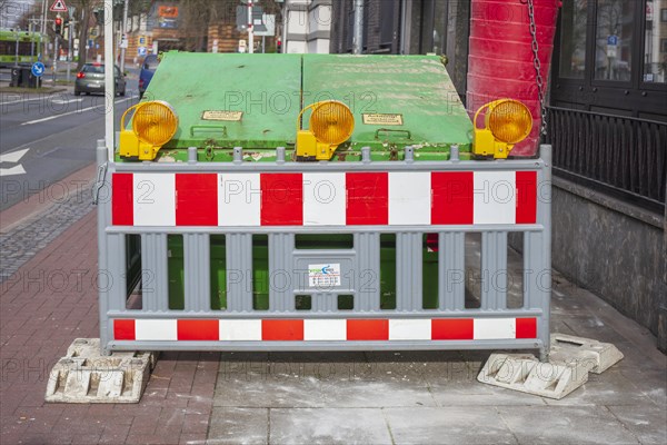 Construction site with barrier and waste container or skip for building rubble on a footpath, Germany, Europe