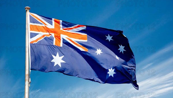 The flag of Australia flutters in the wind, isolated against a blue sky