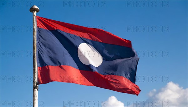 The flag of Laos flutters in the wind, isolated against a blue sky