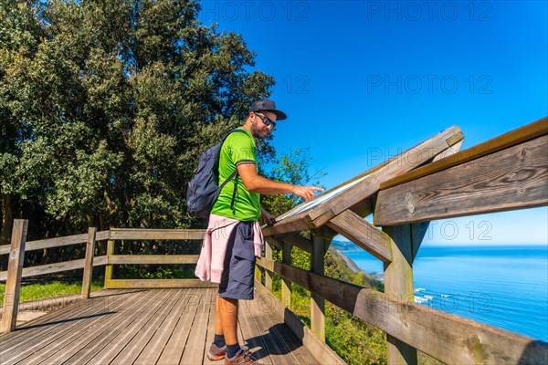 A tourist looking at an information panel in the Zumaia flysch on a trek, Gipuzkoa. Basque Country