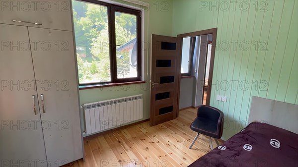 Interior of a bedroom in a new house with green walls and wooden floor