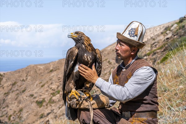 Traditional Kyrgyz eagle hunter with eagle in the mountains, hunting, near Bokonbayevo, Issyk Kul region, Kyrgyzstan, Asia